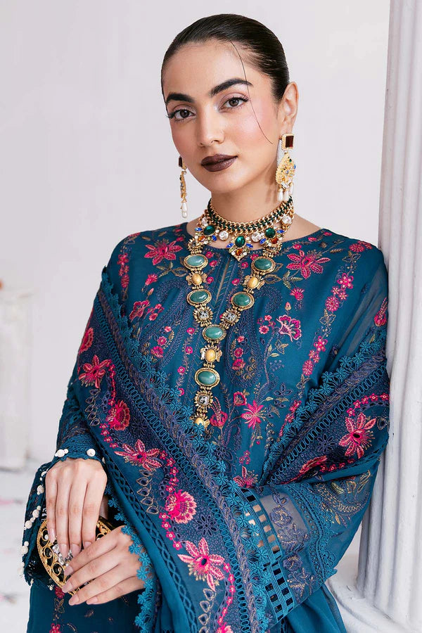 Woman wearing a blue embroidered dress with floral patterns and gold jewelry.