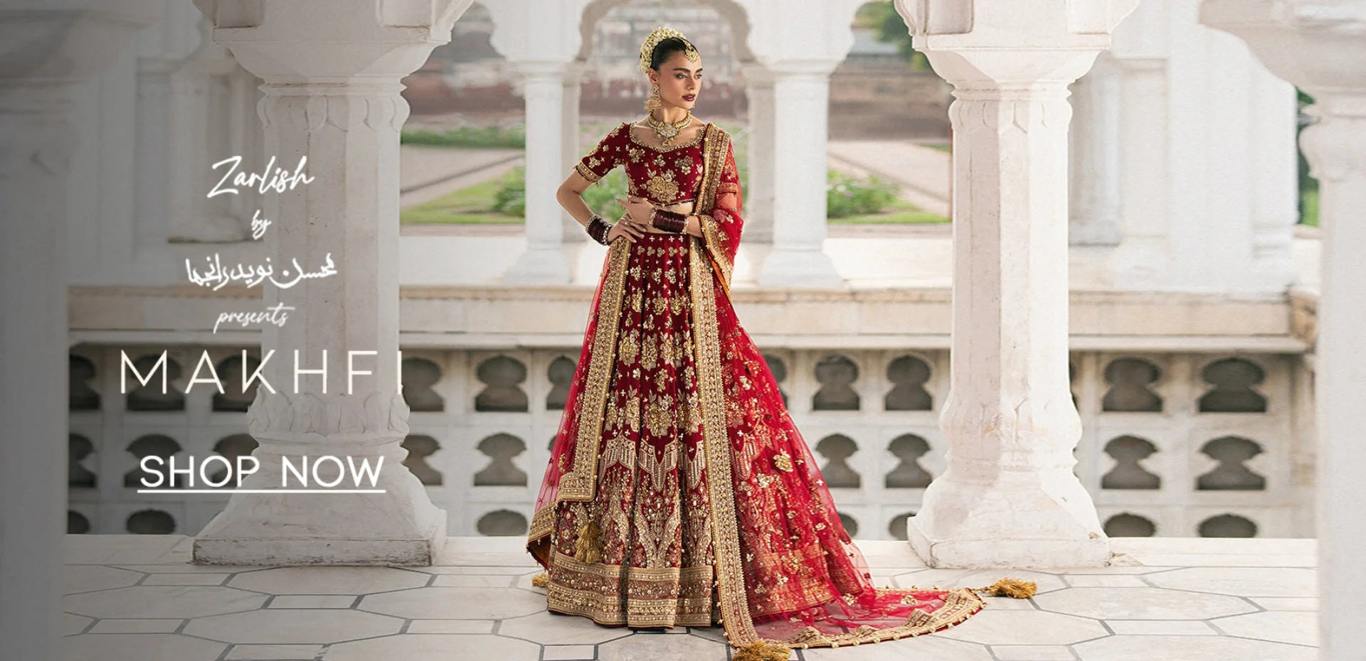 Woman in a red and gold traditional outfit standing in an elegant outdoor setting with architectural columns.