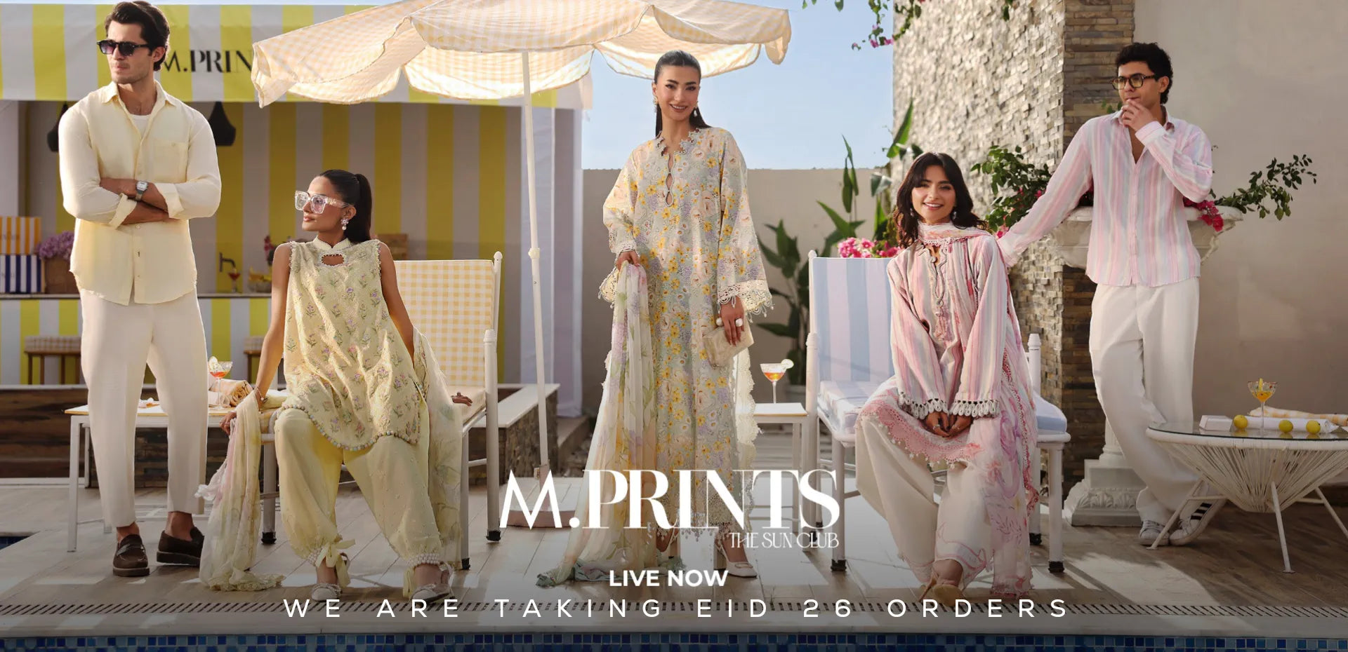 Promotional image of a fashion brand with models in outdoor setting, featuring 'Maria B M. Prints' branding Eid Dresses.