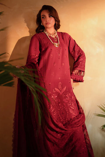 Woman wearing a red embroidered traditional outfit with gold jewelry against a warm-toned background.